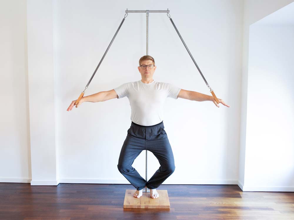 Das Foto zeigt den Pilatestrainer Christian Dorn, im Pilatesstudio 'Powerhouse Potsdam', während einer korrekt ausgeführten Übung um das Gleichgewicht zu trainieren nach dem Originalvorbild von Joseph Pilates.